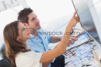 Young photo editors pointing at a computer screen