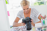 Blonde photo editor looking at a digital camera