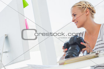 Attractive photo editor looking at a digital camera