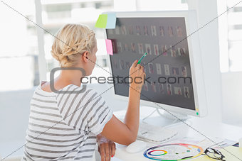 Photo editor pointing at a computer with photos