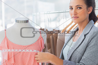 Pretty fashion designer measuring dress
