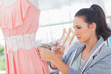 Attractive fashion designer cutting dress
