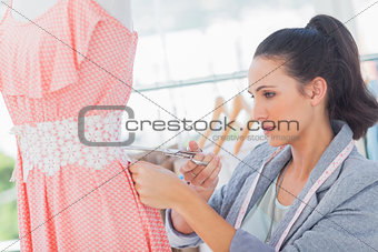 Attractive fashion designer cutting dress