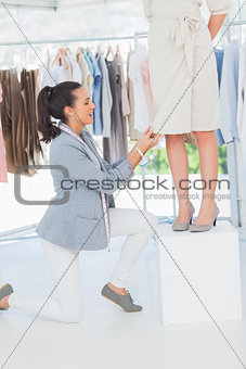 Pretty fashion designer adjusting dress on a model