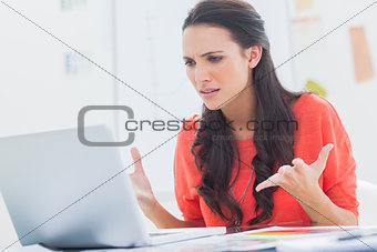 Annoyed designer gesturing in front of her laptop