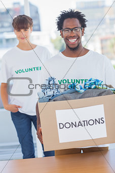 Handsome man holding donation box next to a colleague