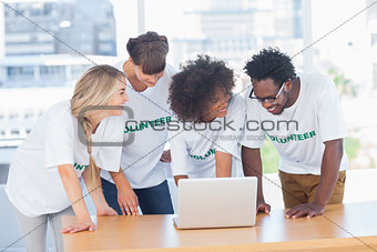 Smiling volunteers working together on a laptop