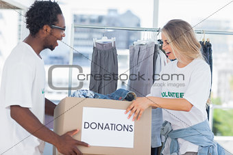 Cheerful volunteers looking at a donation box
