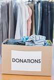 Donations box full of clothes in front of clothes rail