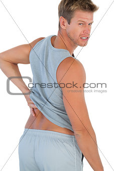 Muscled man grimacing because of a back pain