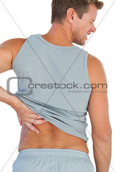 Man in tank top rubbing his back because of a back pain