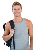 Smiling man in sportswear holding backpack