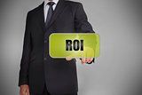 Businessman selecting green tag with the word roi written on it