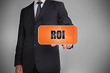 Businessman touching orange tag with the word roi written on it