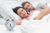 Tired couple looking at the alarm clock