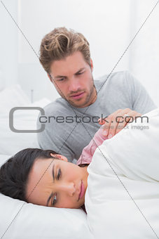 Upset woman ignoring her partner in her bed