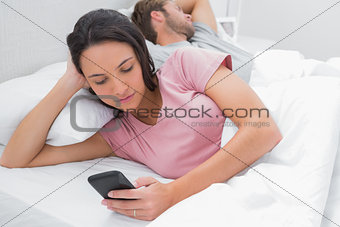 Woman texting while her partner is sleeping