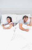 Woman looking at camera while next to her sleeping partner