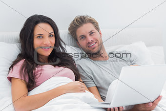 Couple using a laptop in their bed