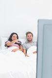 Woman changing channel in her bed