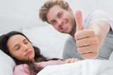 Man giving thumb up while his wife is sleeping