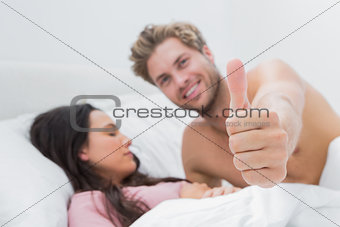 Man giving thumb up next to his sleeping wife