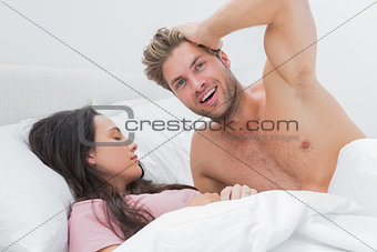 Shirtless man posing next to his sleeping partner