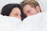Couple under the duvet looking at each other