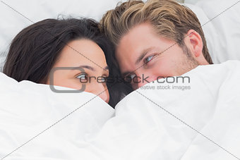 Couple under the duvet looking at each other