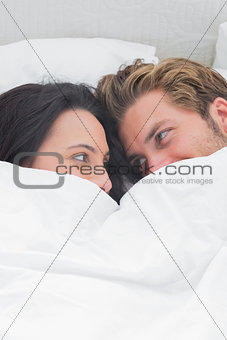 Couple under the quilt looking at each other