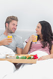 Cheerful couple having breakfast in bed