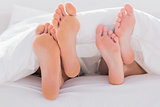 Couples feet crossed under the duvet