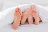 Couple rubbing their feet together under the duvet