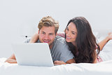 Woman embracing husband while using a laptop