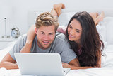 Attractive woman embracing husband while using a laptop