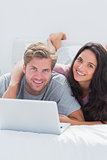 Happy woman embracing husband while using a laptop