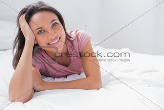 Cheerful woman lying and holding her head