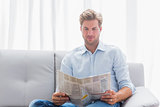 Man reading a newspaper on a couch