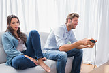 Man playing video games next to his annoyed partner