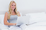 Woman sitting on her bed while using her laptop