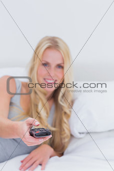 Blonde woman pointing the remote control at the camera