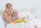 Blonde mother reading a story to her daughter