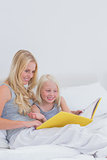 Cheerful mother and daughter reading a story together
