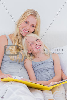 Mother holding a story book with her daughter