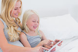 Cheerful mother and daughter using a tablet