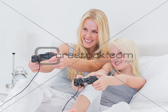 Cheerful mother and daughter playing video games