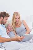 Beautiful couple using a laptop with their daughter