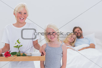 Children bringing breakfast in bed to their parents