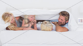 Happy family under the duvet playing