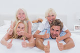 Parents giving piggy back to their children while giving thumbs up